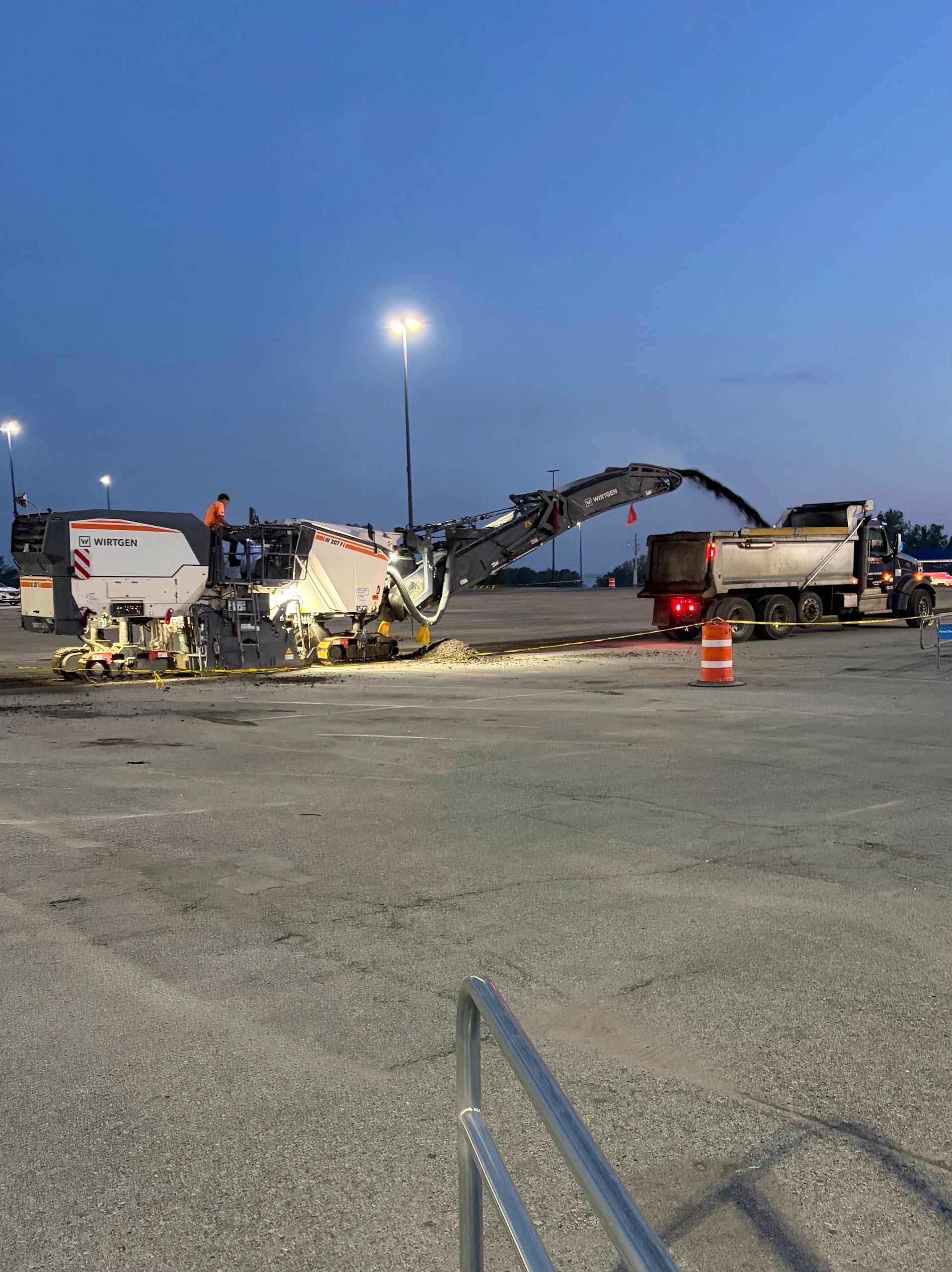 Asphalt milling machine removing surface pavement in a parking lot